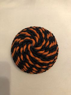 an orange and black rope ball sitting on top of a white table