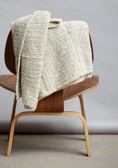 a white blanket sitting on top of a wooden chair