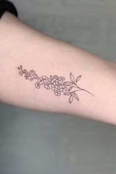 a woman's arm with flowers and leaves tattoo on the left side of her arm