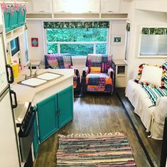 a kitchen with two couches and a rug on the floor in front of a window