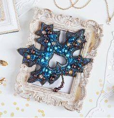 a blue beaded brooch sitting on top of a white table next to other items