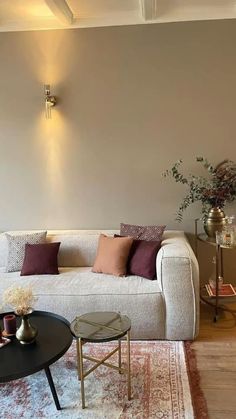 a living room with couches, tables and vases on the floor in front of a wall