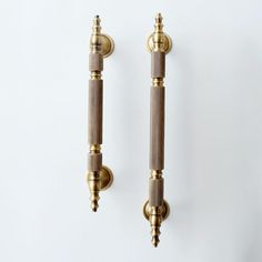 two brass - plated candlesticks hang on a white wall, one is turned off