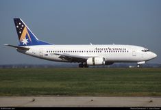 an australian airliner on the tarmac with grass in the foreground and trees in the background