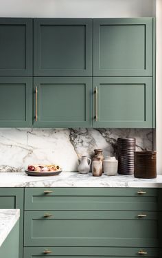 a kitchen with green cabinets and marble counter tops