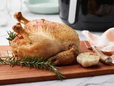 a whole chicken sitting on top of a wooden cutting board