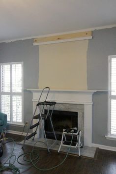 a living room with a fire place and ladders on the floor in front of it