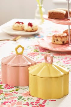 there are three cakes on the table with pink and yellow containers next to each other