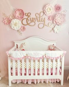 a baby crib with pink and white flowers on the wall