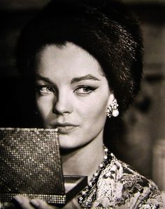 an old photo of a woman holding a mirror in front of her face and looking at the camera