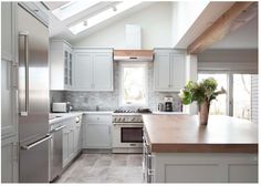 a kitchen with white cabinets and stainless steel appliances in the middle of an open floor plan