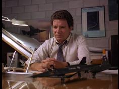 a man sitting at a desk in front of a model airplane