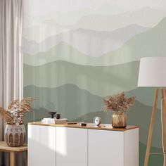 a living room scene with focus on the sideboard and wallpaper that has mountains painted on it