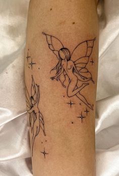 a tattoo on the leg of a woman with a flower and two fairy wands