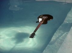 an electric guitar floating in the water with its neck hanging off it's side