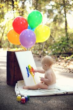 a baby sitting on the ground painting with balloons