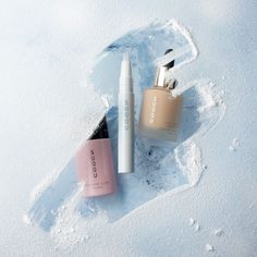 three different types of beauty products in the snow, one is pink and one is white