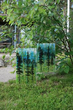 two blue and green art pieces hanging from a tree