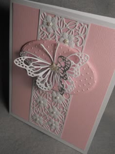 a pink and white greeting card with a butterfly on it's back, sitting on a table