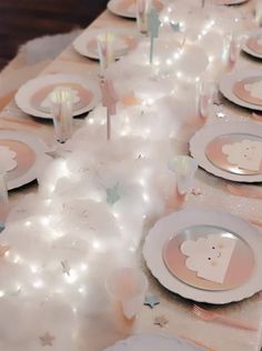 a table set for a baby shower party with white plates and pink napkins on it