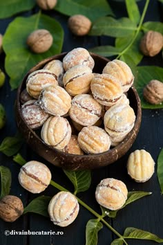 a bowl filled with almonds next to leaves and nuts