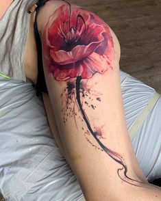 a woman with a tattoo on her arm has a red flower painted on the thigh