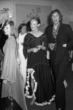 black and white photograph of people dressed up in fancy clothing at a party with drinks