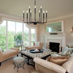 a living room filled with furniture and a chandelier hanging from the ceiling over a fire place