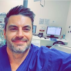 a man in scrubs is smiling at the camera