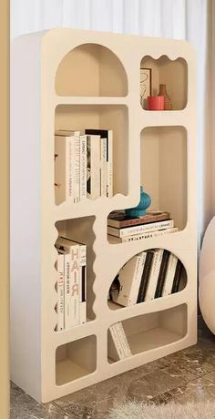 a book shelf with several books on top of it in front of a white wall