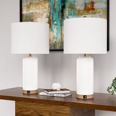 two white lamps sitting on top of a wooden table