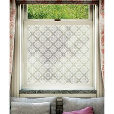 a living room with a couch and window covered in roman blind shades, next to a green lawn