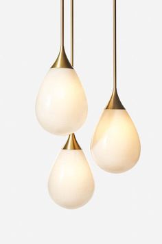 three white and gold pendant lights hanging from the ceiling