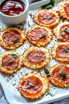 small pizzas on a tray with sauce and herbs