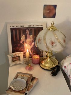 a white table topped with a lamp next to a book and magazine on top of it