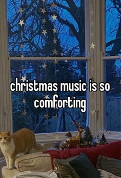 a cat sitting on top of a couch in front of a window with the words christmas music is so comforting