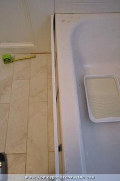 a bath tub sitting next to a window in a bathroom with tile flooring and white walls