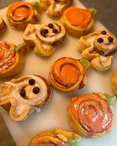 there are many small pastries on the table with orange icing and chocolate chips