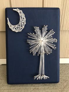 a string art piece with a crescent hanging from it's side next to a pinwheel