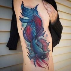 a woman's stomach with a colorful fish tattoo on it