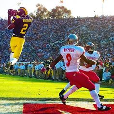 two football players jumping up in the air to catch a ball while others watch from the stands