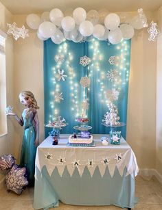 a frozen princess themed birthday party with balloons and streamers on the wall, table