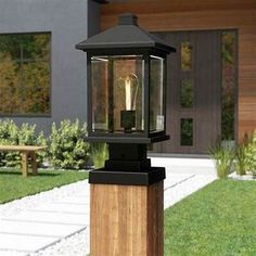 an old fashioned lantern sitting on top of a wooden post in front of a house