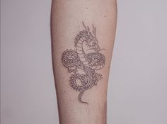 a tattoo on the leg of a person with a dragon design on it's arm