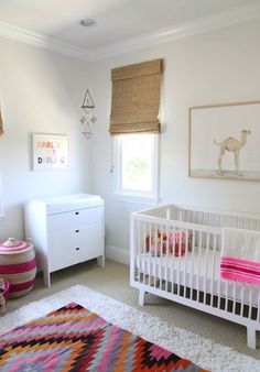 a baby's room with a crib, dresser and rug in the corner