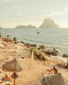 beach chairs and umbrellas are on the sand near the water