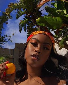 a woman holding an orange in her right hand and wearing a headband on top of her head