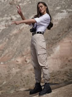 a woman in white shirt and khaki pants pointing at something