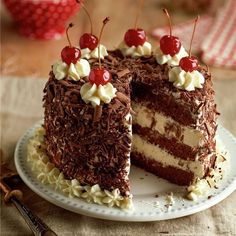 a chocolate cake with white frosting and cherries on top is cut in half