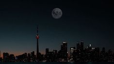 a full moon is seen over the skyline of toronto, on a clear night with no clouds